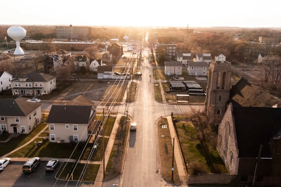 Aerial view of Gary, Indiana at golden hour with prominent white bulbous water tower on left historic stone church on the right.